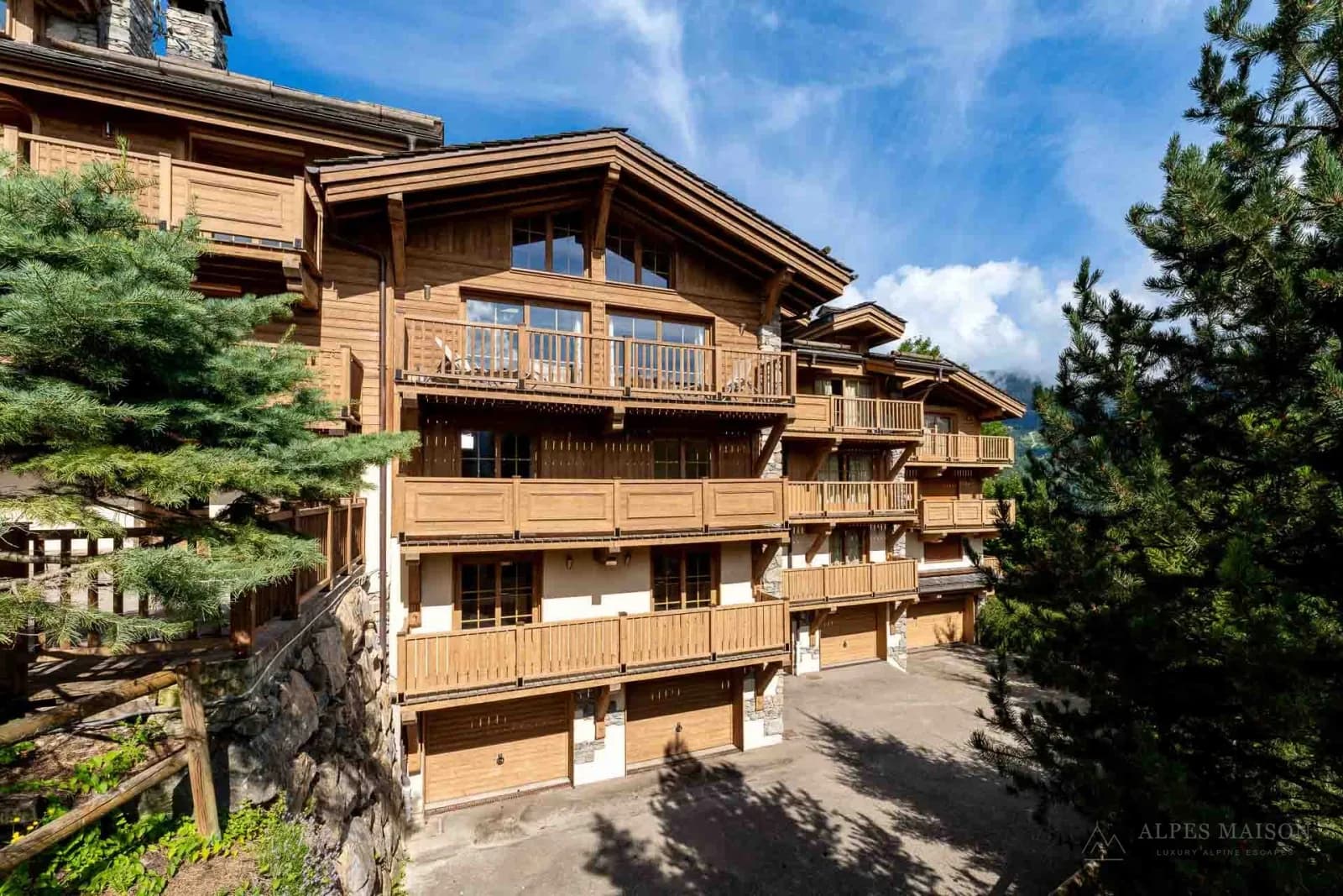 Holzbalkone und Steinfassade des Le Praz Chalet in Courchevel, umrahmt von Nadelbäumen