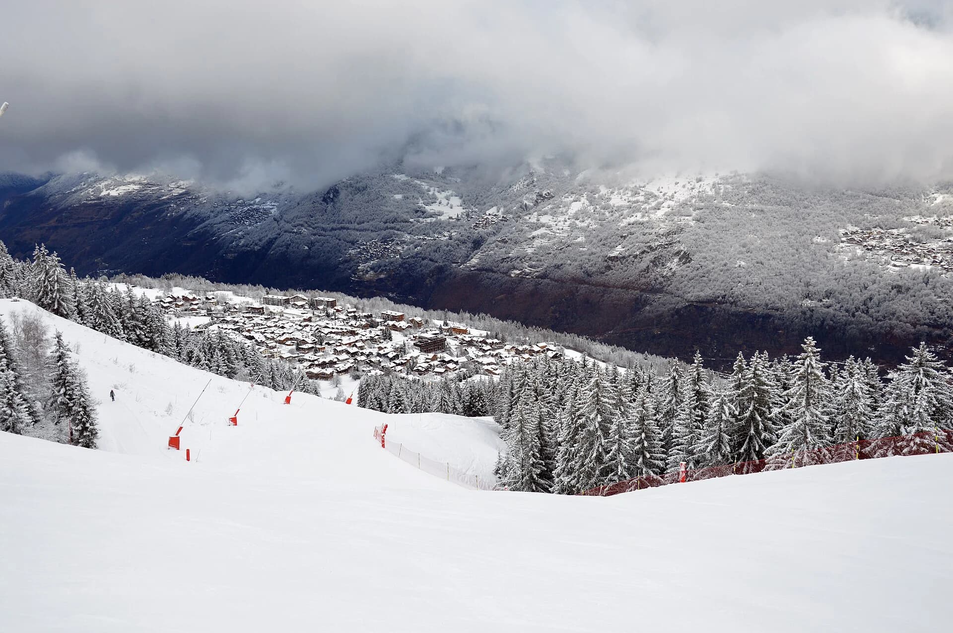 Snow-covered Courchevel Le Praz village beneath wooded mountain slopes